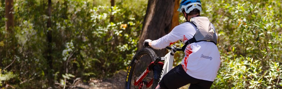 Mountainbiker mit albek Haul Three Trinkrucksack bei einer Abfahrt im Wald