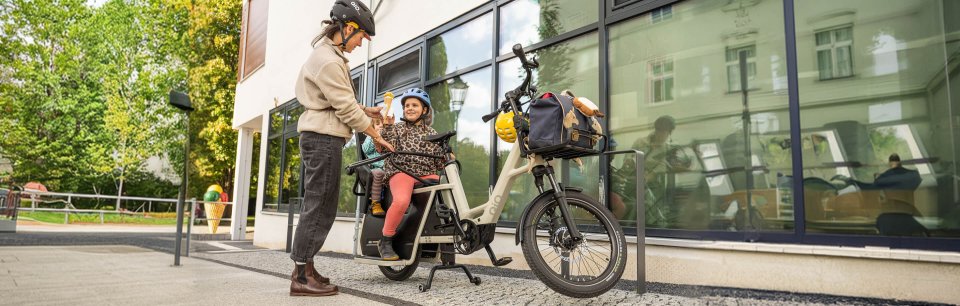 Ein QiO Bike mit Kindersitzen im Stadtumfeld steht für flexible und sichere Transportlösungen im Familienleben.