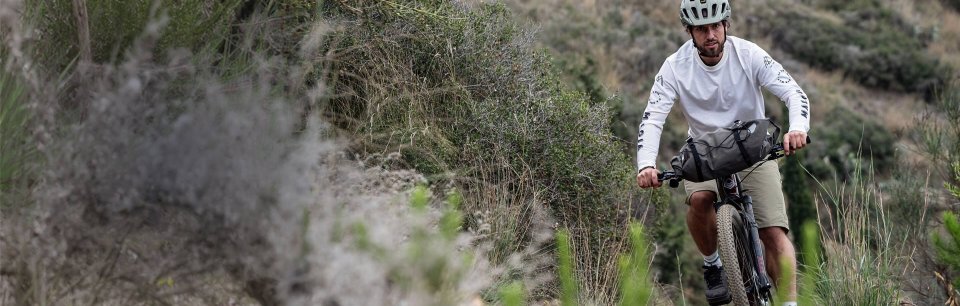 Zwei Radreisende genießen eine Mahlzeit neben vollbepackten Rädern mit ORTLIEB Taschen