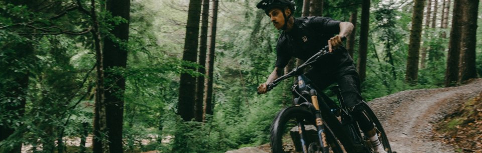 Ein Mountainbiker fährt mit einem Haibike Trailbike dynamisch durch einen Waldpfad.