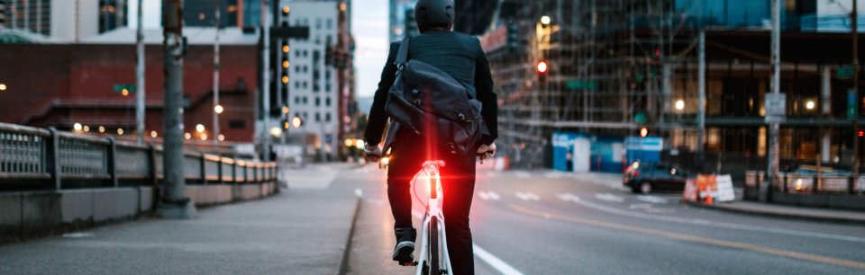 Ein Radfahrer fährt mit dem Alps Alpine Ride Safety System RS 1000, einem Rücklicht mit integrierter Kamera, durch die Stadt.