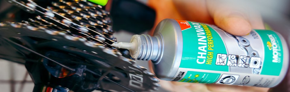 Persona che lubrifica la catena con un flacone di lubrificante Motorex