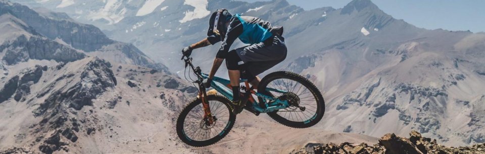 Persona in sella a una MTB metre fa un'acrobazia su sterrato