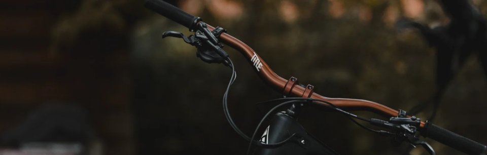 Hochwertiger MTB-Lenker von Title Bike Parts in mattem Kupferton im Outdoor-Setting.