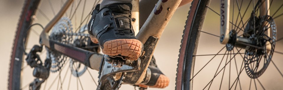 Un cycliste Gravel porte des chaussures UDOG noires.