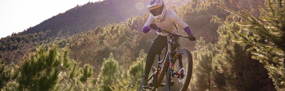 Ciclista in sella alla sua bici con abbigliamento e attrezzatura downhill dedicata