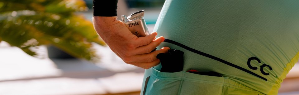 Gros plan sur un cycliste qui glisse une barre énergétique Styrkr dans la poche arrière de son maillot de cycliste.