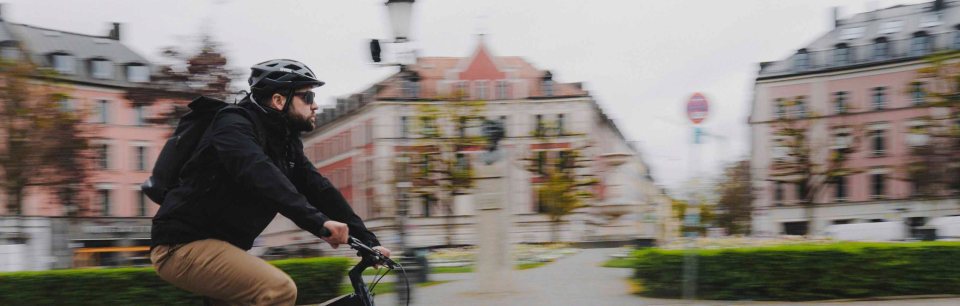 Ein Pendler fährt mit uvex Helm und Brille durch die Stadt und zeigt sicheren und komfortablen Schutz im Alltag.