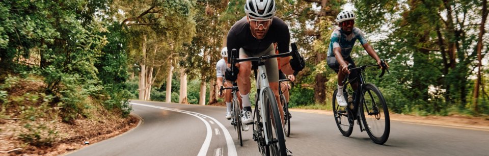 Une équipe de cyclistes dynamiques en tenue ASSOS qui fonce à travers un paysage verdoyant.