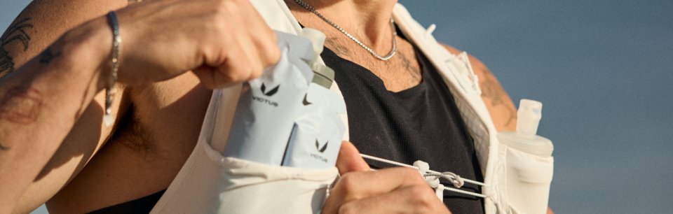 Lähikuva Victus-energiageelipusseista, joita henkilö ottaa ulos juoksuliivin olkahihnataskusta.