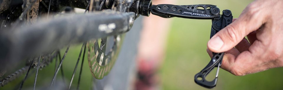 Persona con una herramienta de bolsillo de Leatherman arreglando una bicicleta
