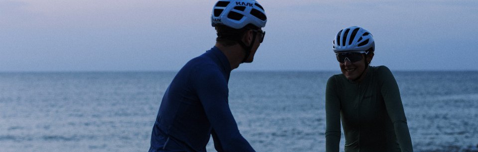Two cyclists riding along the coast wearing Santini cycling apparel