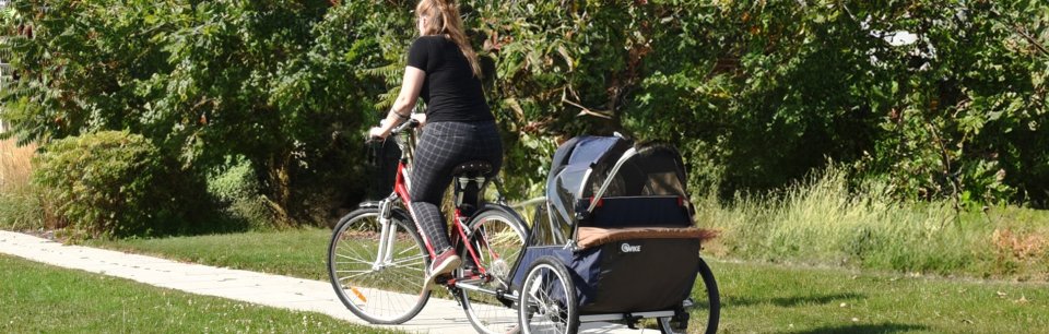 Mujer en bicicleta con un remolque para niños de la marca Wike