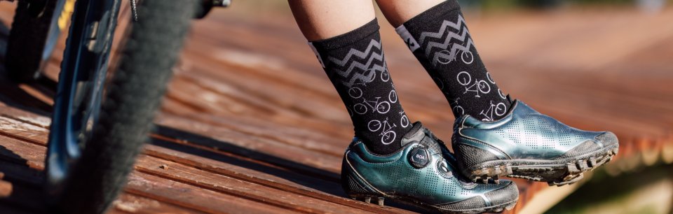 Stijlvolle fietssokken van Sox Footwear met MTB-schoenen op een houten steiger.