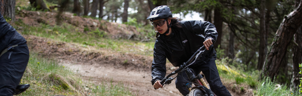 Vauhdikasta toimintaa – Pyöräilijä Alpina-pyöräilykypärässä ja -suojalaseissa ajaa alas mutkikasta metsäpolkua