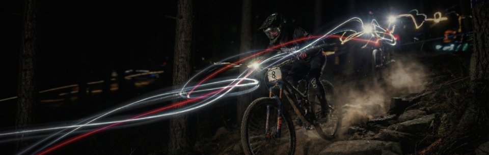 Ein Radfahrer mit einer unter dem Lenker montierten Lampe fährt einen Trail hinunter.