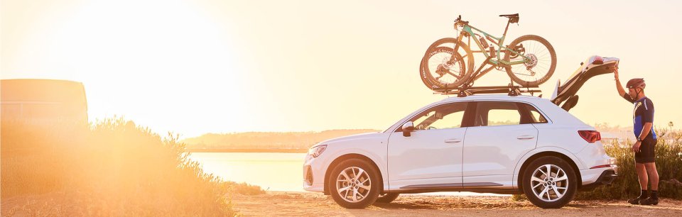 Bikes mounted on a CRUZ roof bike rack on a white SUV at sunset