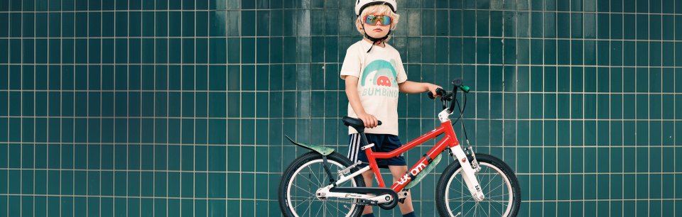 Niño con su bicicleta ropa y pared de azulejos verdes