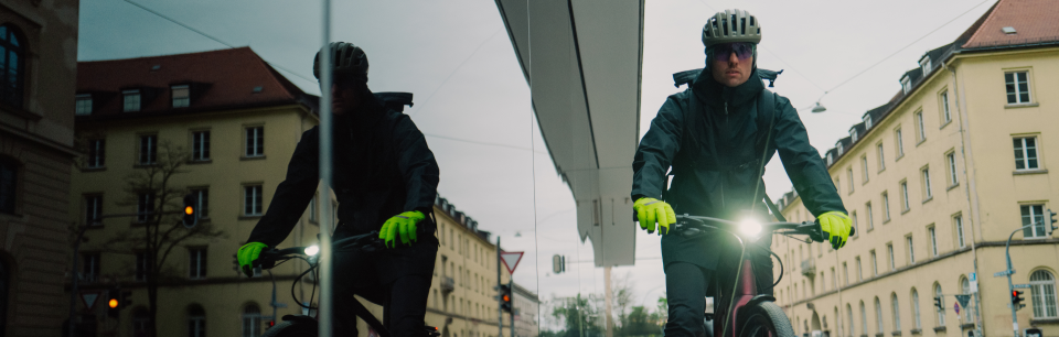 Persona con guantes de invierno Roeckl montando en bicicleta por la ciudad.