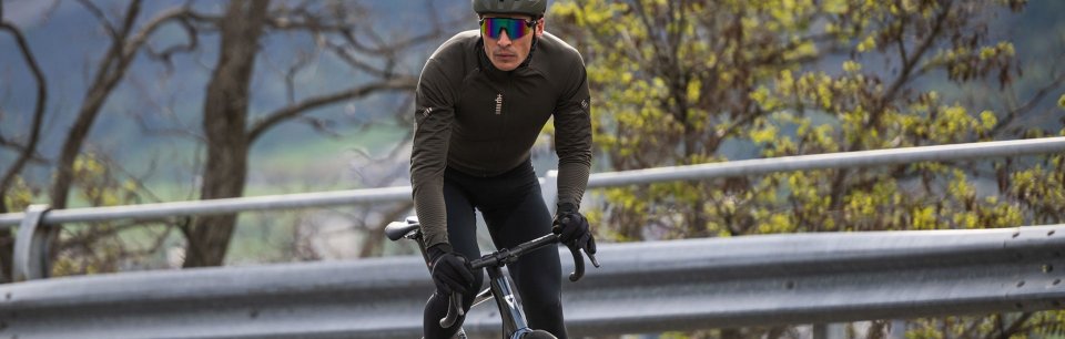 Mann trägt eine rh+ Fahrradjacke und fährt konzentriert auf einem Rennrad.